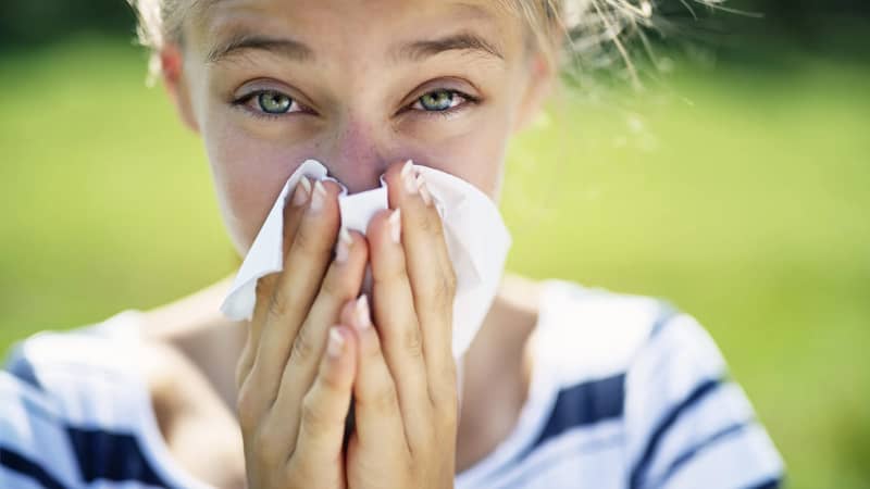 Person with seasonal allergies using tissue